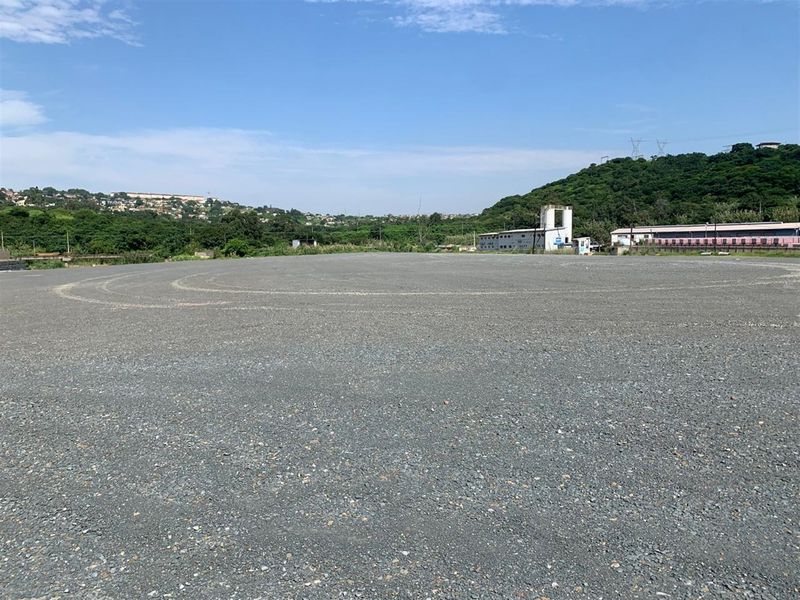 A wide, level commercial vacant land plot featuring a compacted gravel surface, suitable for various development opportunities.