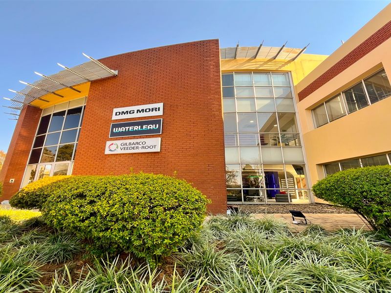 Modern commercial office building exterior featuring a prominent brick facade, large glass curtain walls, and professional landscaping.