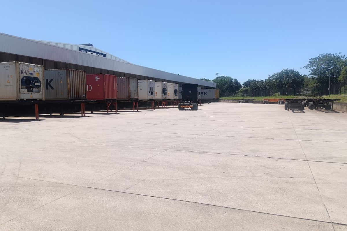 Large industrial concrete yard with loading bay access and warehouse facility.