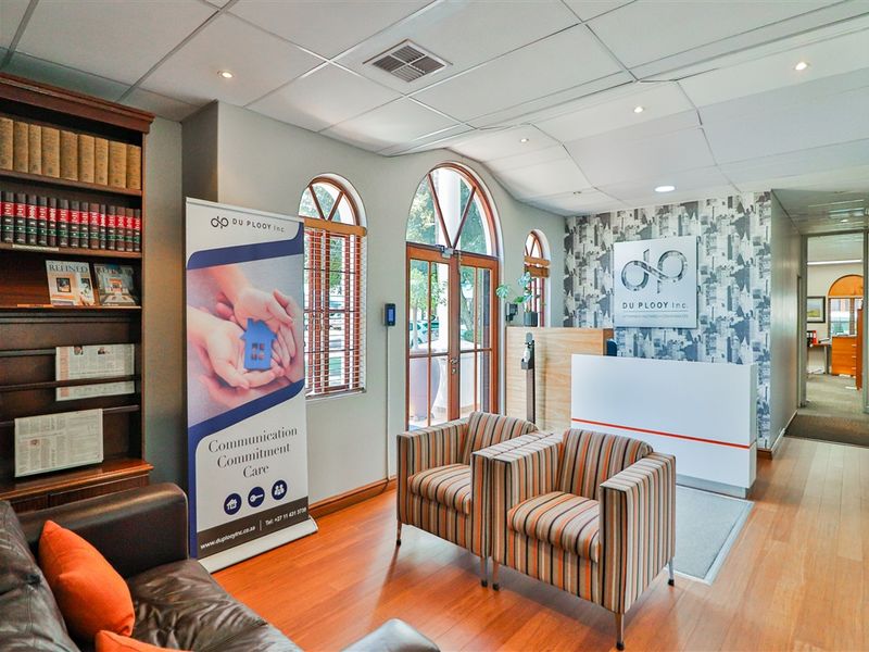 Professional commercial reception area featuring a built-in desk, arched windows, laminate flooring, and a dedicated waiting space with integrated shelving.