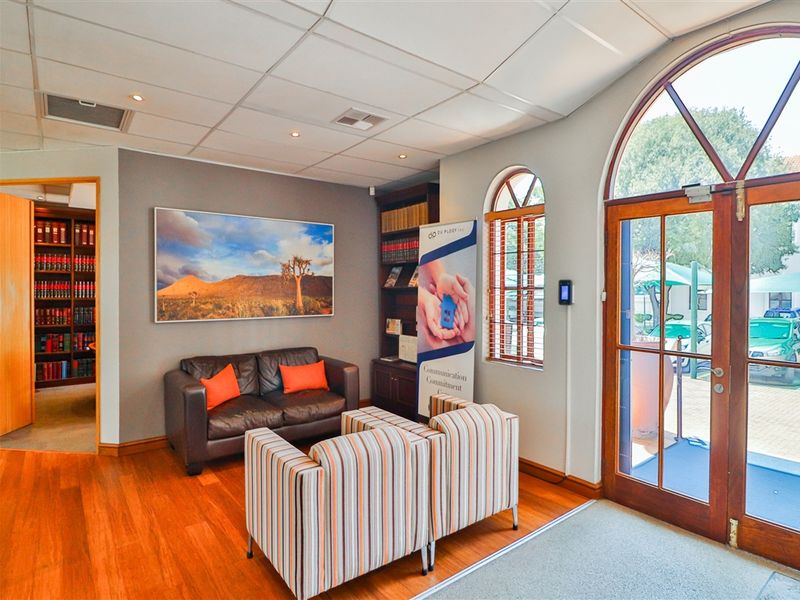 Welcoming commercial reception area featuring timber flooring, built-in shelving, and an arched glass entrance door providing natural light.