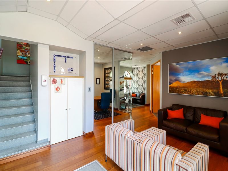 Professional commercial reception area featuring hardwood flooring, a glass-partitioned office space, built-in storage, and a staircase leading to an upper level.