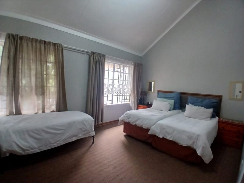 Spacious bedroom featuring high vaulted ceilings, large windows with security bars, and neutral wall finishes.