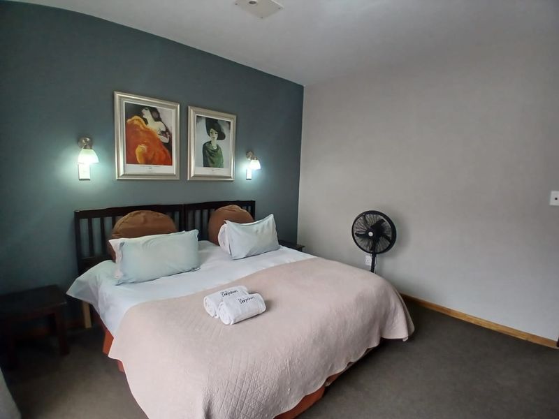 A bedroom featuring a dark accent wall, wall-mounted lighting fixtures, and neutral carpeting.