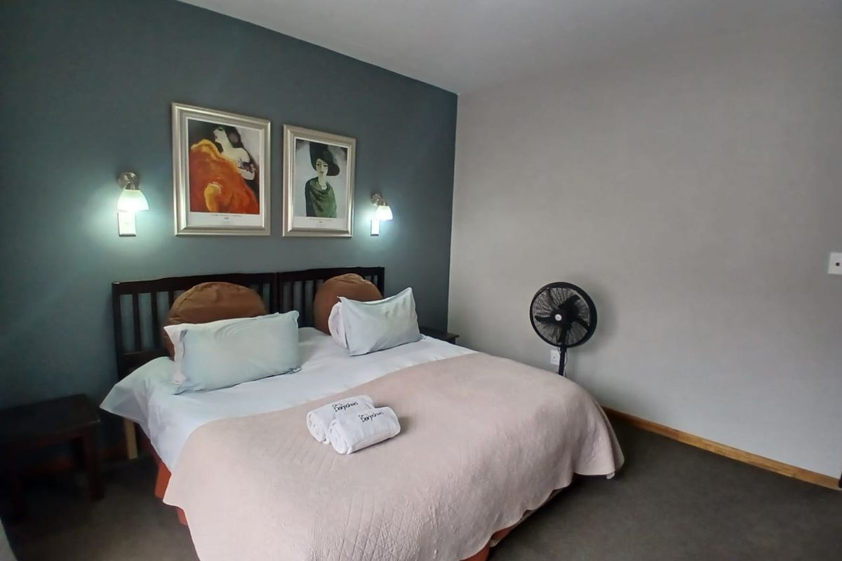 A bedroom featuring a dark accent wall, wall-mounted lighting fixtures, and neutral carpeting.