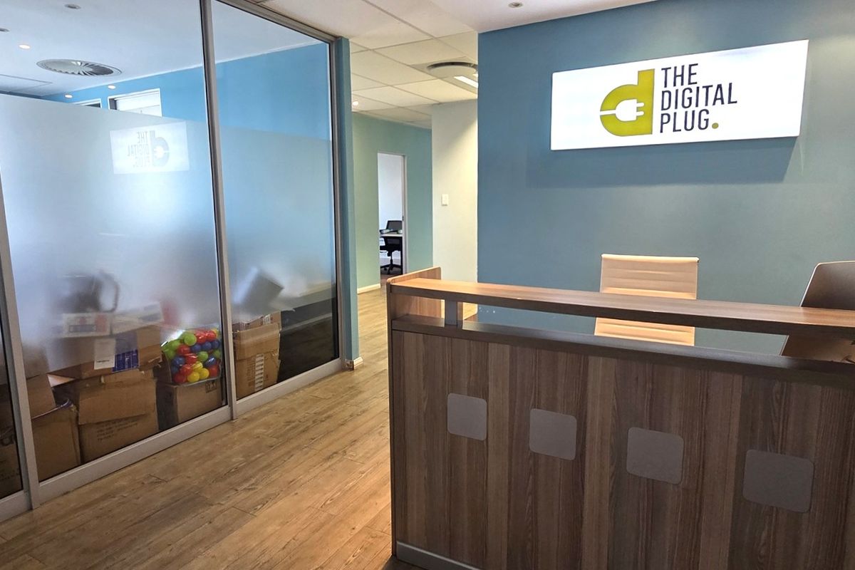 Professional office reception area featuring a built-in reception desk, modern glass partitioning, and clean laminate flooring with integrated lighting.