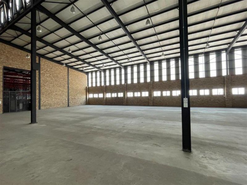 Spacious industrial warehouse unit featuring exposed steel structural framing, high ceilings, concrete flooring, and abundant natural light through clerestory windows.