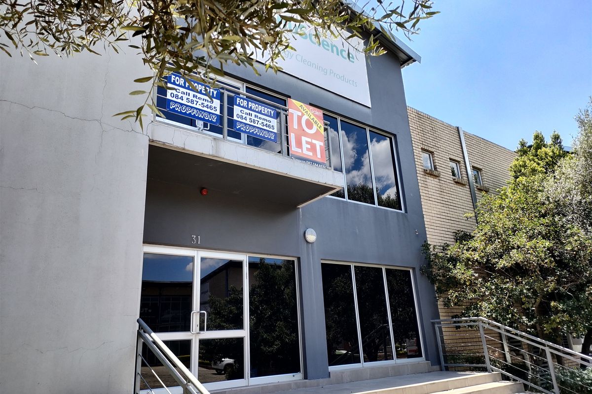 Front elevation of a commercial industrial building featuring a glass storefront, concrete entrance stairs, and a balcony area.