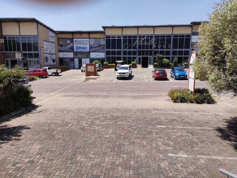 Front exterior view of a commercial industrial complex featuring paved parking, large glass storefronts, and a secure entrance.