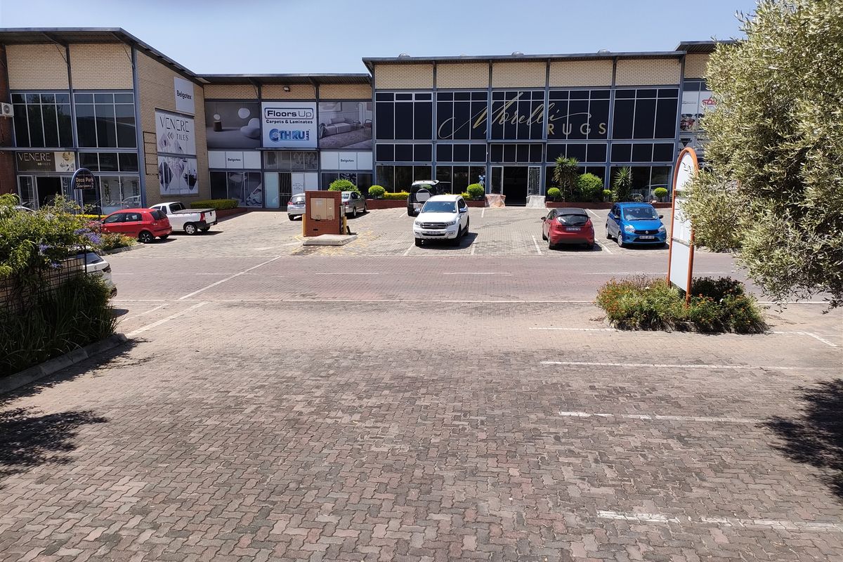Front exterior view of a commercial industrial complex featuring paved parking, large glass storefronts, and a secure entrance.