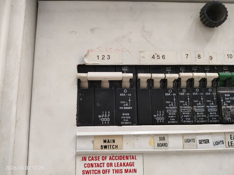 Close-up view of an industrial electrical distribution board with labeled circuit breakers and a main switch, showing signs of wear and exposed housing.