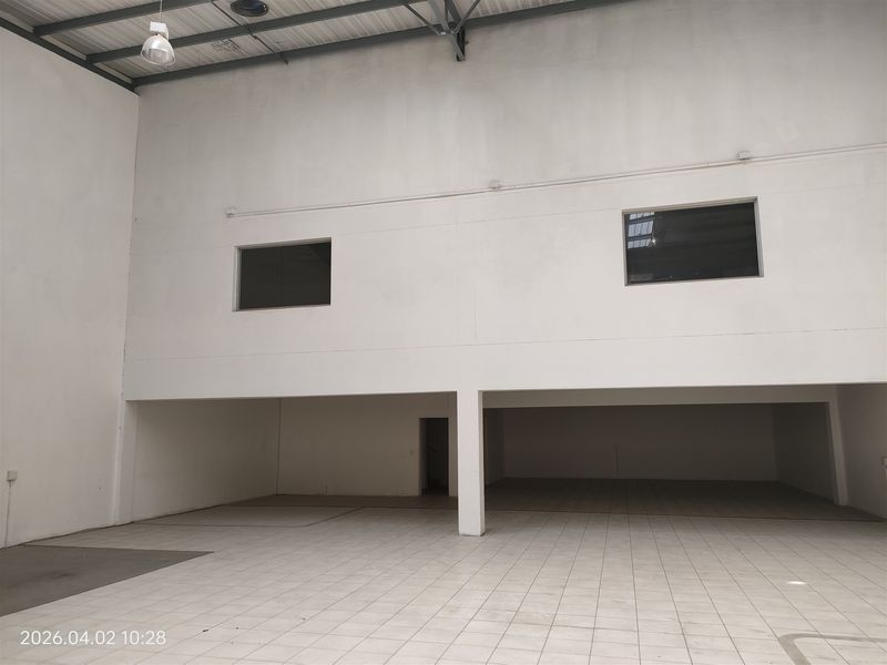 Spacious industrial utility area featuring tiled flooring, high ceilings with exposed steel structure, and internal windows providing natural light.