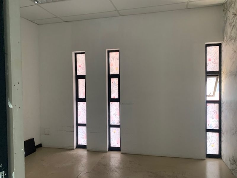 A vacant office space featuring vertical windows with decorative film and a suspended ceiling grid.