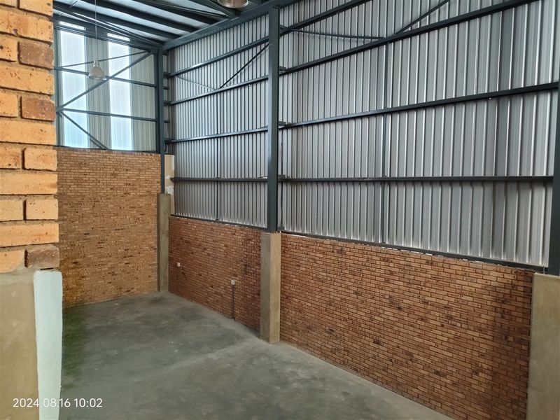 A clean, industrial utility space featuring exposed brick walls, corrugated metal cladding, and a durable concrete floor with high-ceiling steel structural framing.