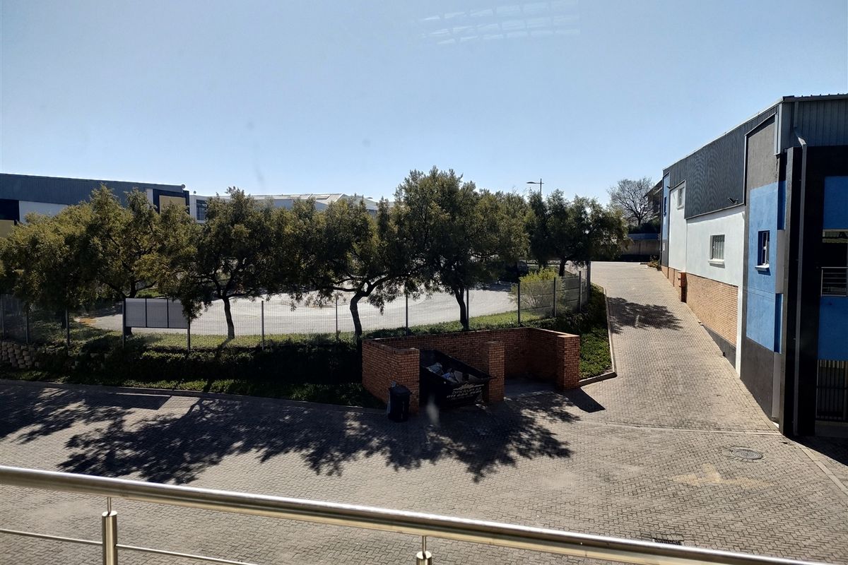 Elevated view of the industrial property's rear paved yard, featuring a brick refuse enclosure, perimeter fencing, and access ramp.