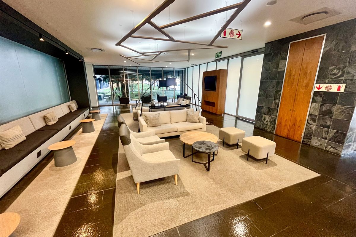 A modern, spacious office lounge area featuring built-in bench seating, stone feature walls, and large glass doors providing ample natural light.