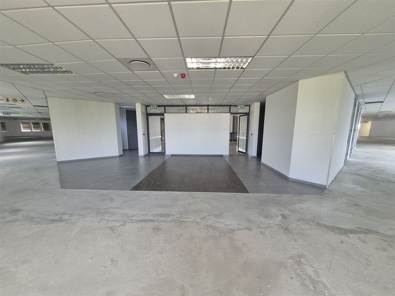 Open-plan office space featuring a suspended ceiling, recessed lighting, and a mix of tiled and laminate flooring, currently in a shell condition.