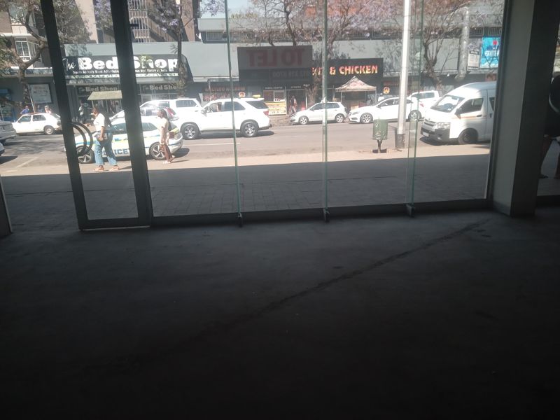 Interior view of a retail space featuring large glass storefront windows looking out onto a busy street.