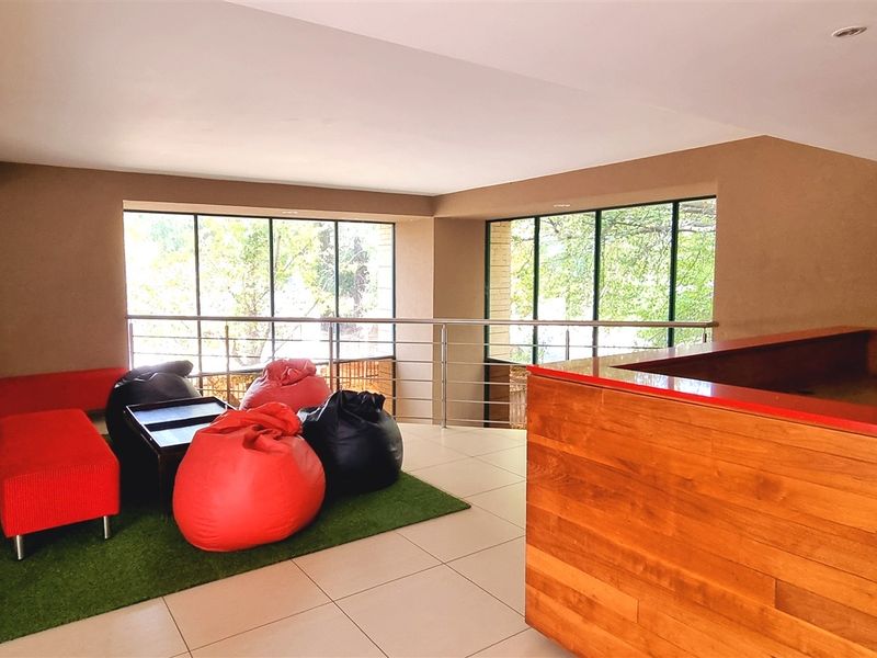 Modern office breakout area featuring a wooden reception desk, stainless steel balustrades, and large windows providing natural light.