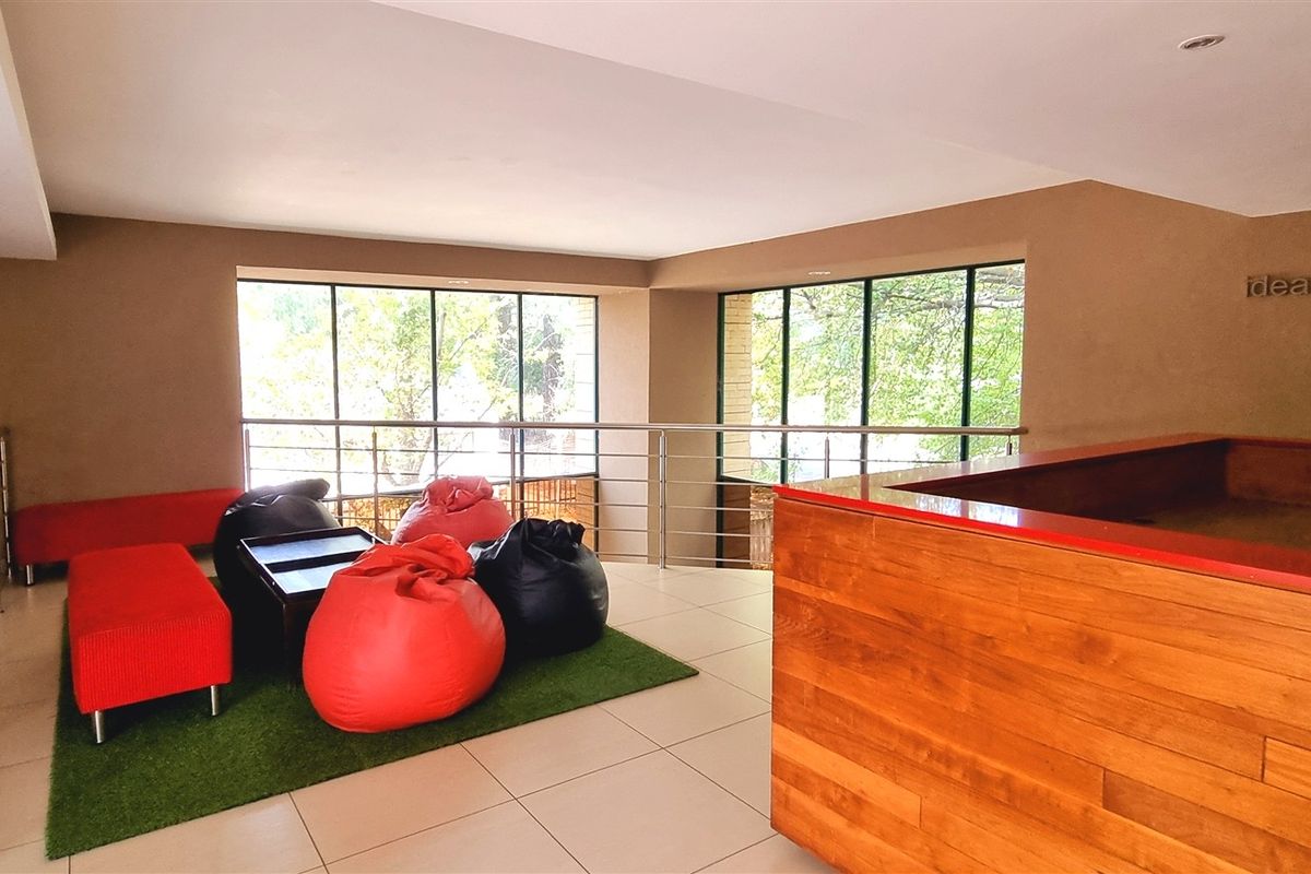 Modern office breakout area featuring a wooden reception desk, stainless steel balustrades, and large windows providing natural light.