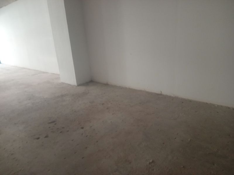 An unfinished retail space featuring raw concrete flooring and plain white walls, offering a blank canvas for custom commercial fit-out.