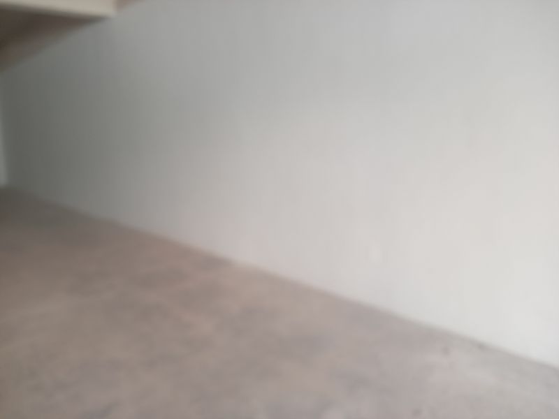 A blurry view of an empty interior space with plain walls and flooring, suitable for various retail or utility purposes.