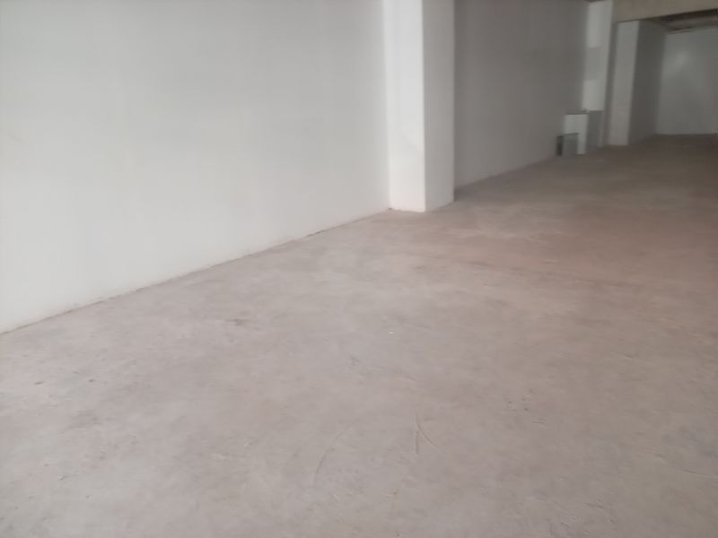 An empty, open-plan retail space featuring unfinished concrete flooring and plain white walls, offering a blank canvas for custom fit-out.