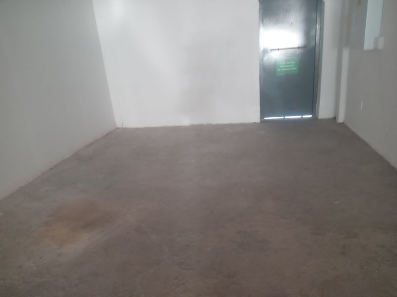An empty, unfinished utility space featuring concrete flooring and a metal emergency exit door.