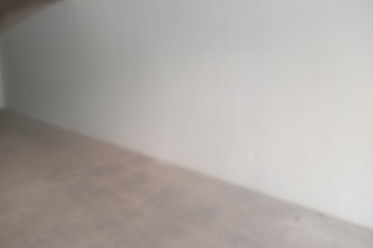 A blurry view of an empty interior space with plain walls and flooring, suitable for various retail or utility purposes.