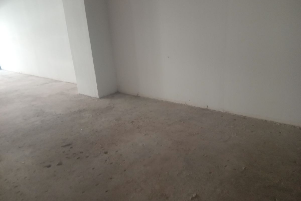 An unfinished retail space featuring raw concrete flooring and plain white walls, offering a blank canvas for custom commercial fit-out.