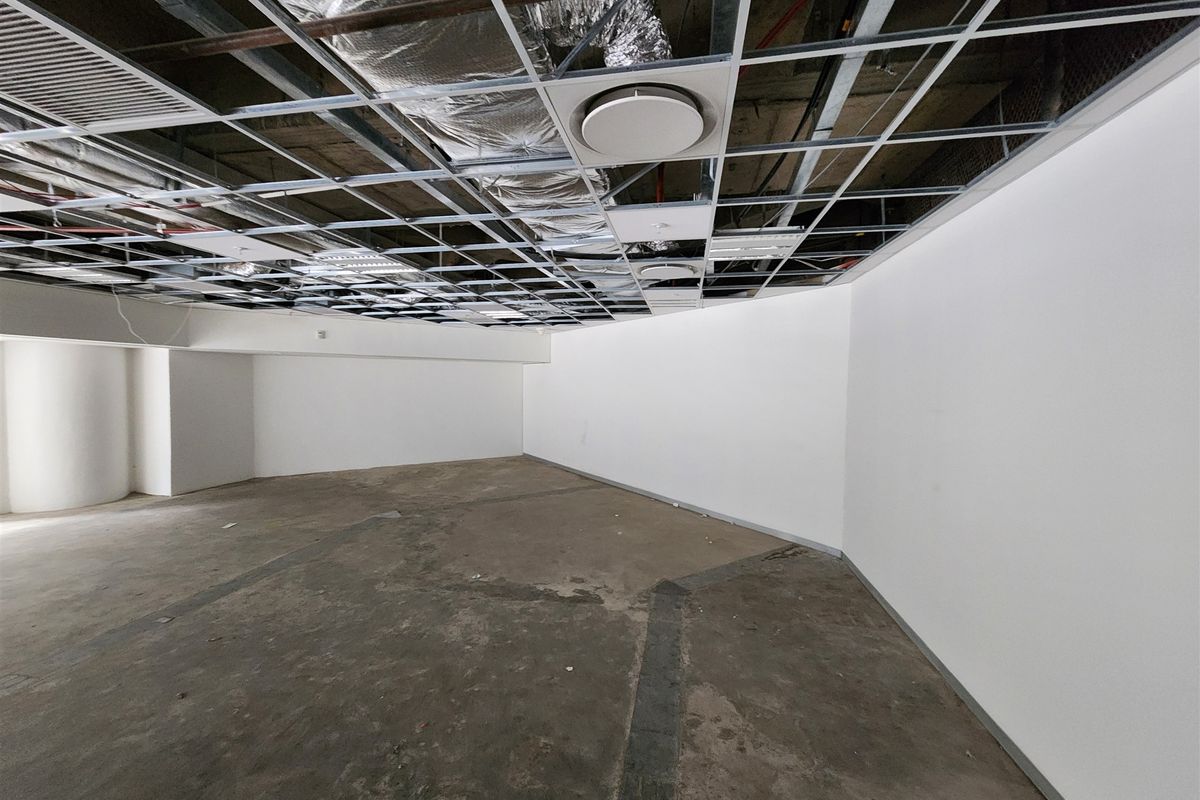 An unfinished open-plan office space featuring an exposed ceiling grid, exposed ductwork, and raw concrete flooring, ready for custom fit-out.