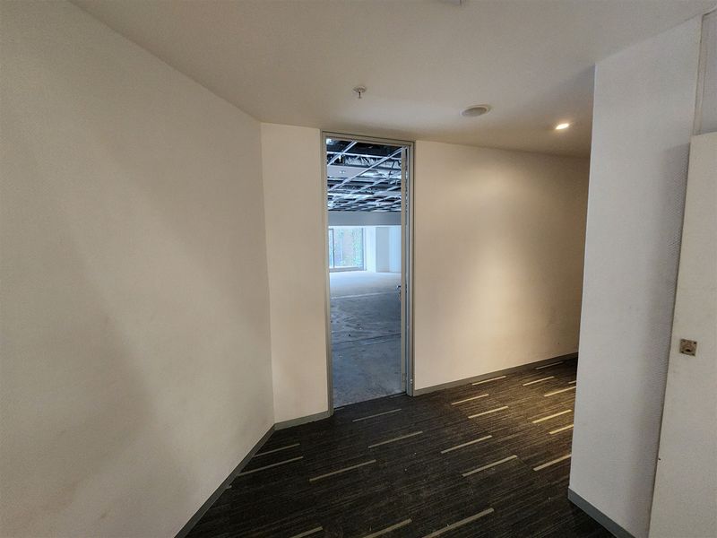 An empty office space featuring carpeted flooring and an unfinished suspended ceiling grid, presenting a blank canvas for custom interior fit-out.
