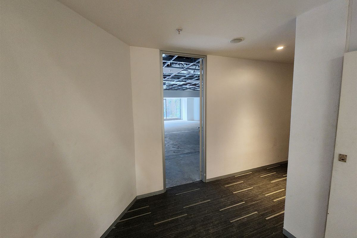 An empty office space featuring carpeted flooring and an unfinished suspended ceiling grid, presenting a blank canvas for custom interior fit-out.