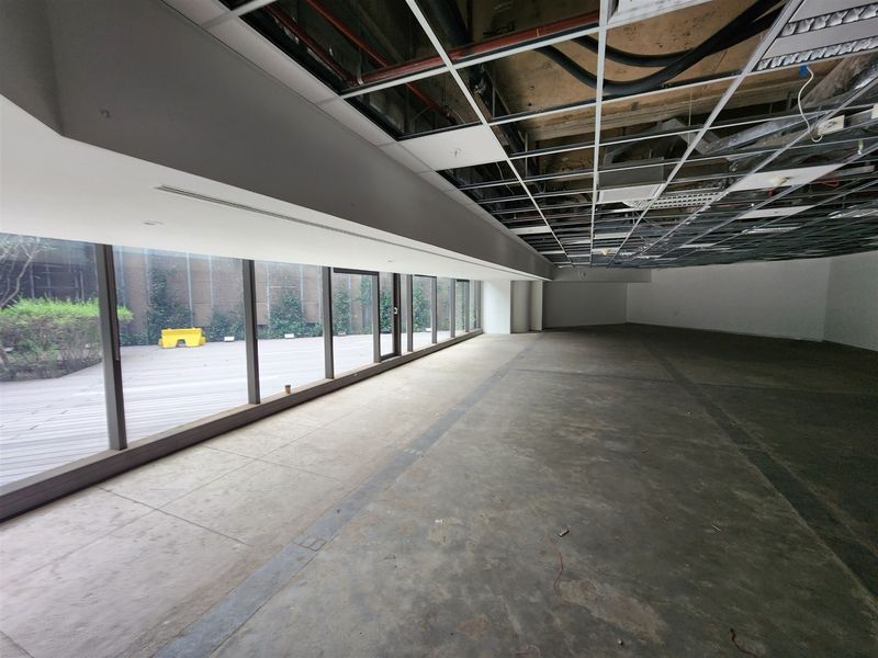 Spacious open-plan office area featuring floor-to-ceiling windows, direct access to an outdoor deck, and an unfinished ceiling ready for custom fit-out.