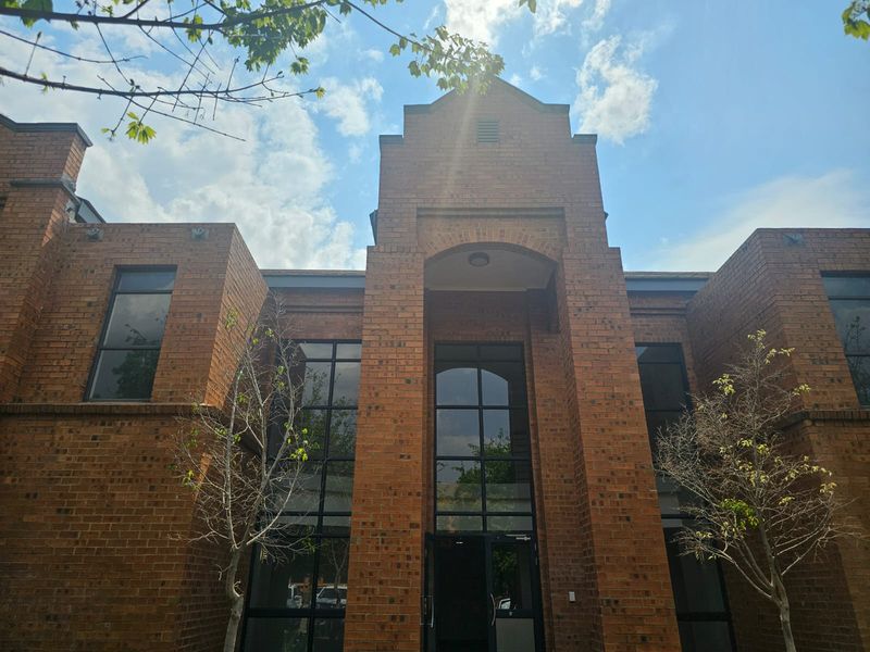 Front elevation of a commercial brick building featuring a prominent double-height entrance and large glass windows.