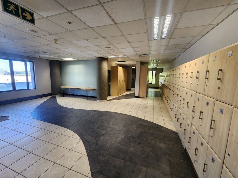 Spacious office area featuring extensive built-in locker storage, durable tiled flooring with a decorative pattern, and functional recessed lighting.
