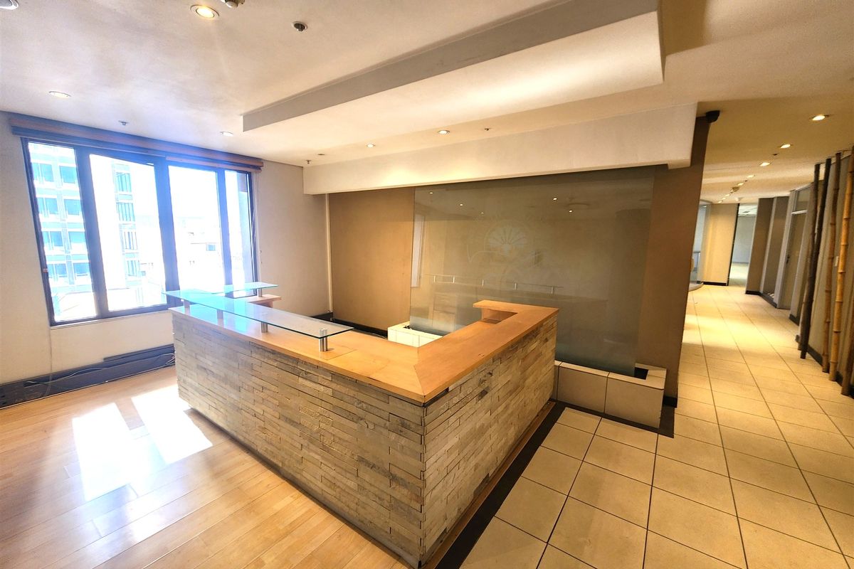 A professional office reception area featuring a built-in stone-clad desk, glass partition, and a mix of tiled and wooden flooring.