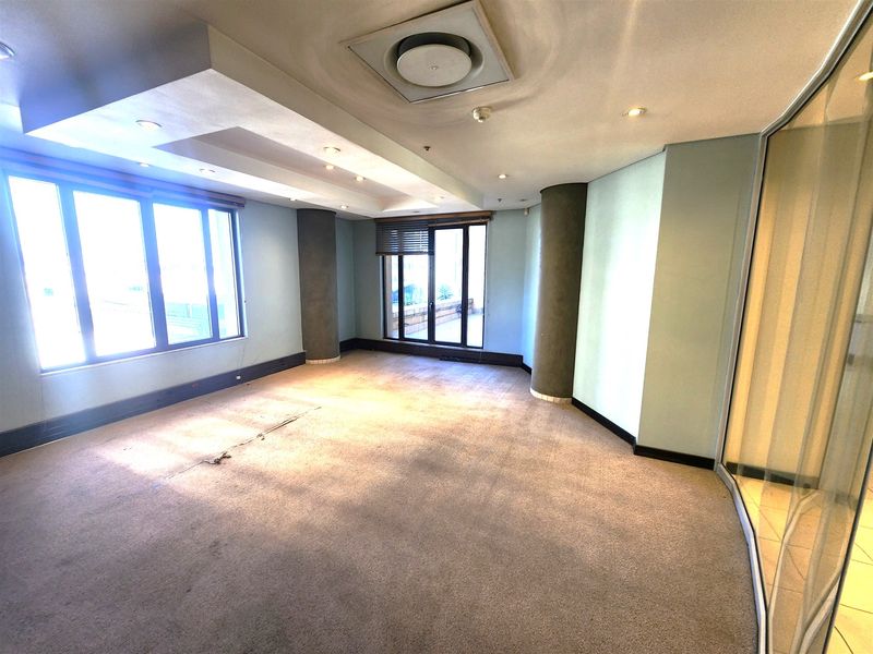 An empty office space featuring recessed ceiling lighting, central air conditioning, large windows, and a glass partition wall.