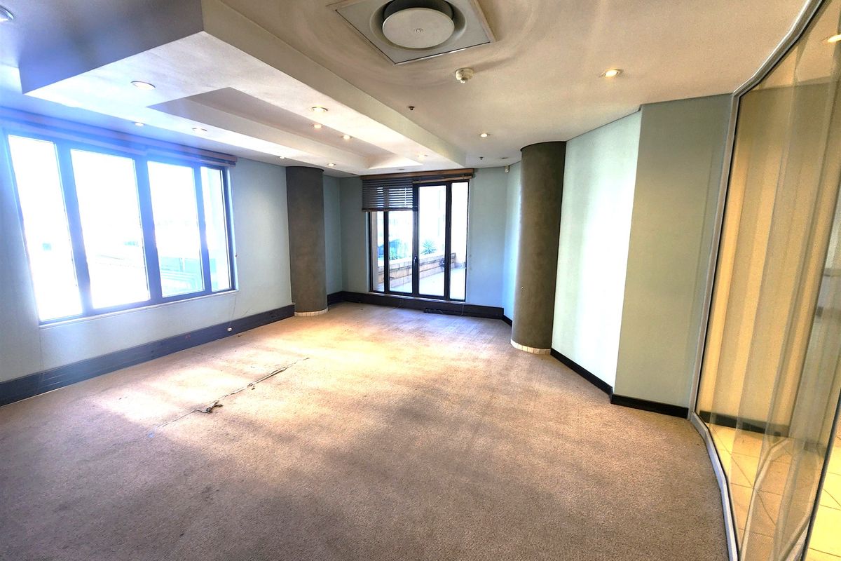 An empty office space featuring recessed ceiling lighting, central air conditioning, large windows, and a glass partition wall.