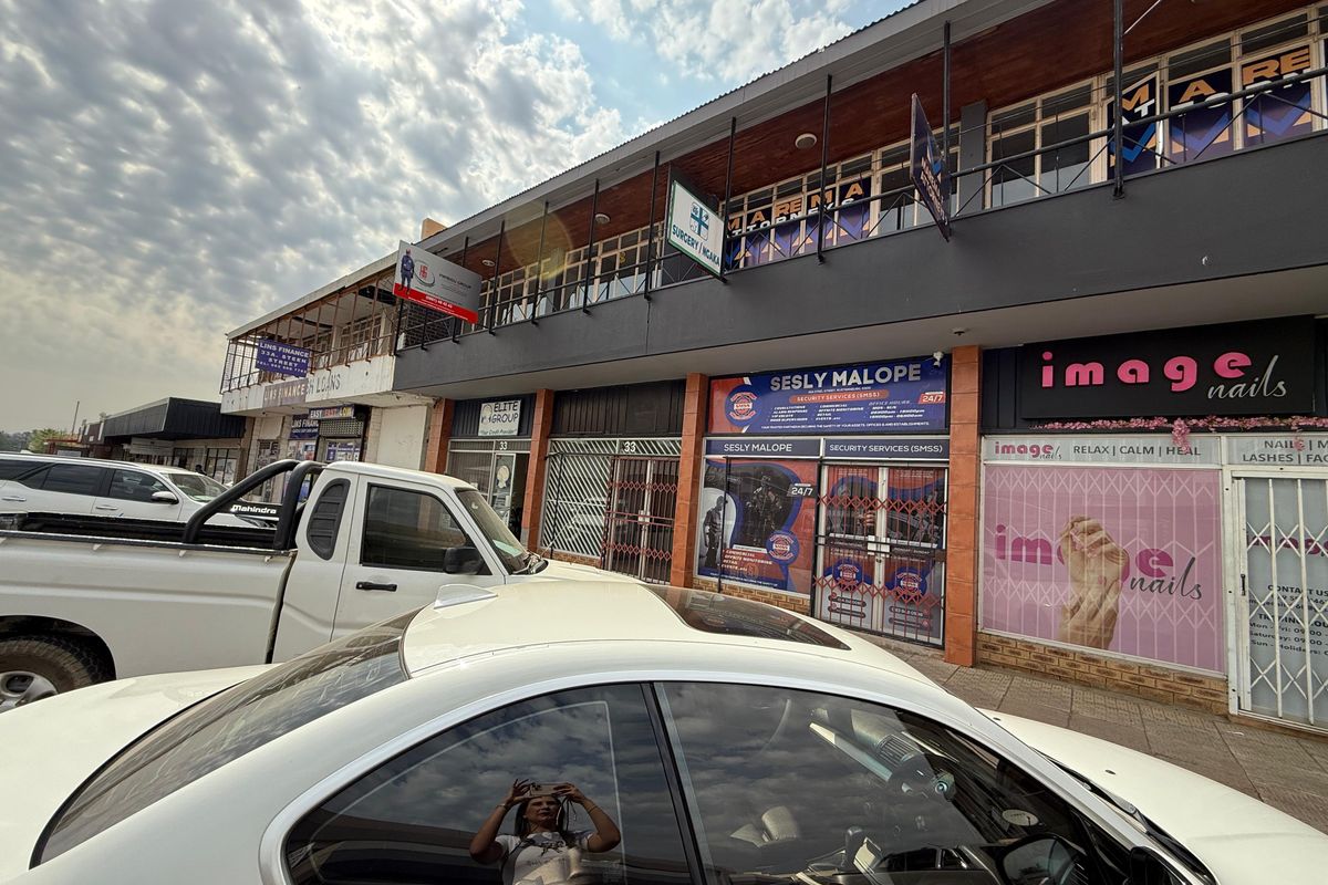 Front exterior view of a multi-tenant commercial office building featuring ground-level storefronts and an upper-level balcony with signage.