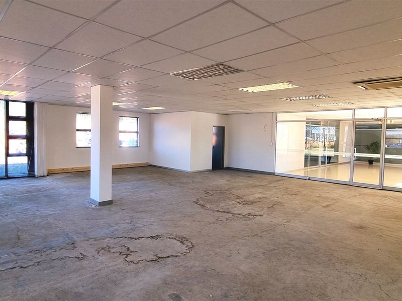 Spacious open-plan office area featuring a suspended ceiling, recessed lighting, glass partitioning, and large windows, currently awaiting new flooring finishes.