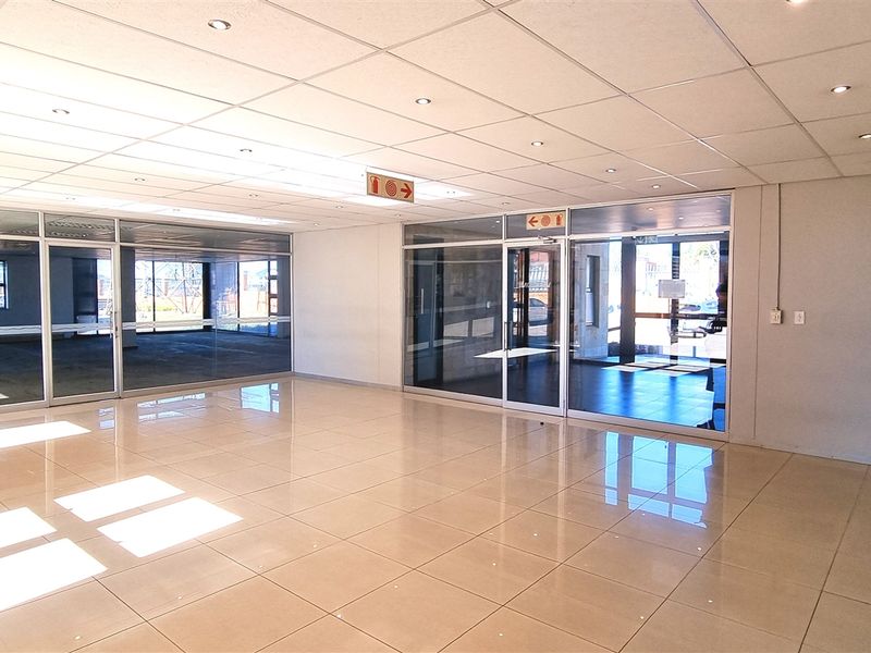Spacious, modern office interior featuring polished tile flooring, suspended ceilings with recessed lighting, and extensive glass partitioning for an open, professional workspace.