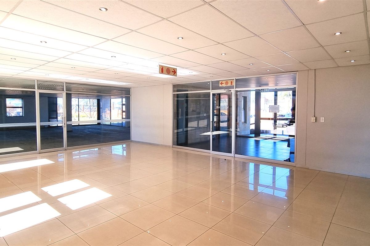 Spacious, modern office interior featuring polished tile flooring, suspended ceilings with recessed lighting, and extensive glass partitioning for an open, professional workspace.