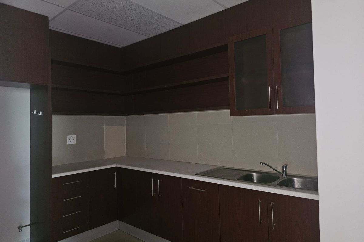 A functional kitchen area featuring dark wood cabinetry, ample storage, laminate countertops, and a double bowl stainless steel sink with a tiled backsplash.