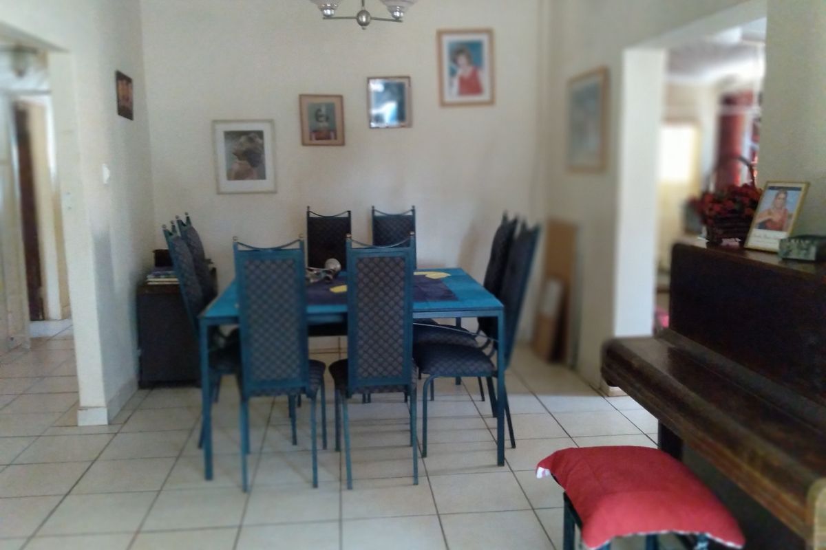 A functional dining room area featuring tiled flooring and a central ceiling light fixture, providing a neutral space for family meals.
