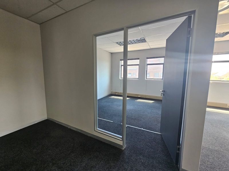 Empty office space featuring carpet flooring, suspended ceilings with recessed lighting, and a glass partition wall providing a professional work environment.
