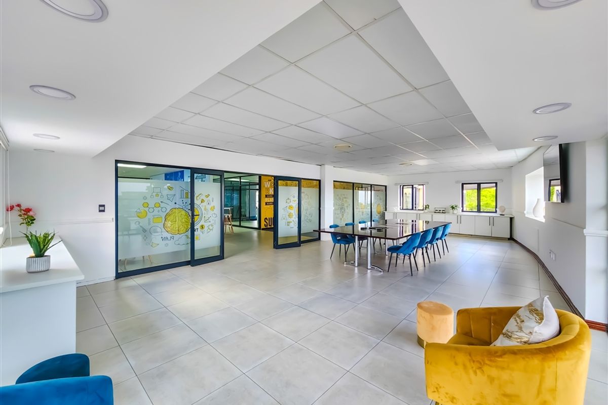 Spacious modern office area featuring glass partitions, suspended ceiling tiles, recessed lighting, and neutral tiled flooring, providing a bright and professional workspace.