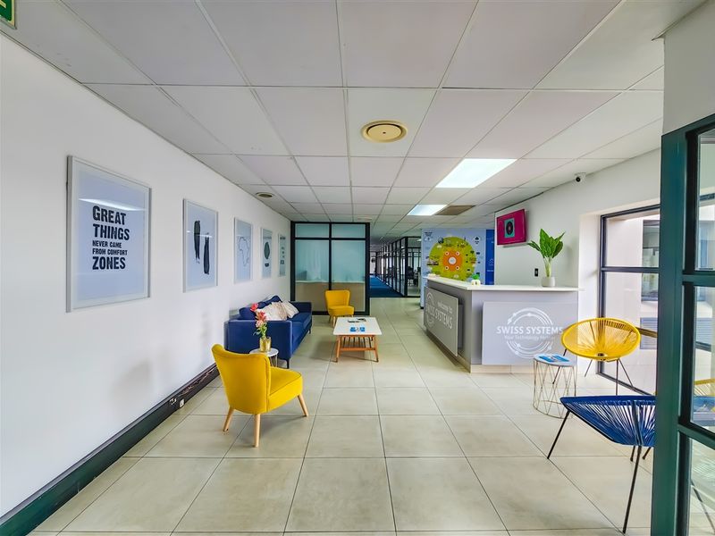 A bright and professional office reception area featuring a built-in reception desk, tiled flooring, and modern glass partitions.