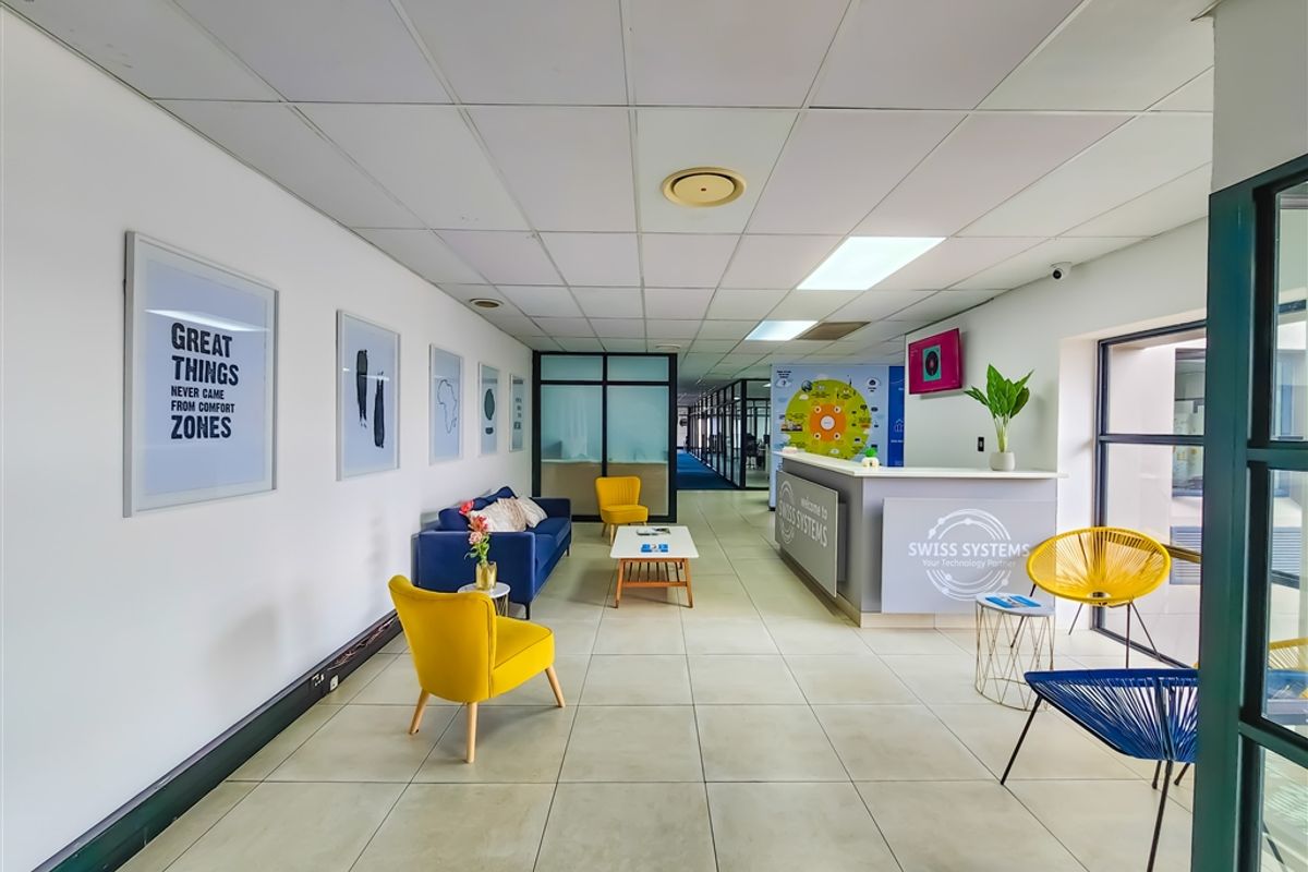 A bright and professional office reception area featuring a built-in reception desk, tiled flooring, and modern glass partitions.