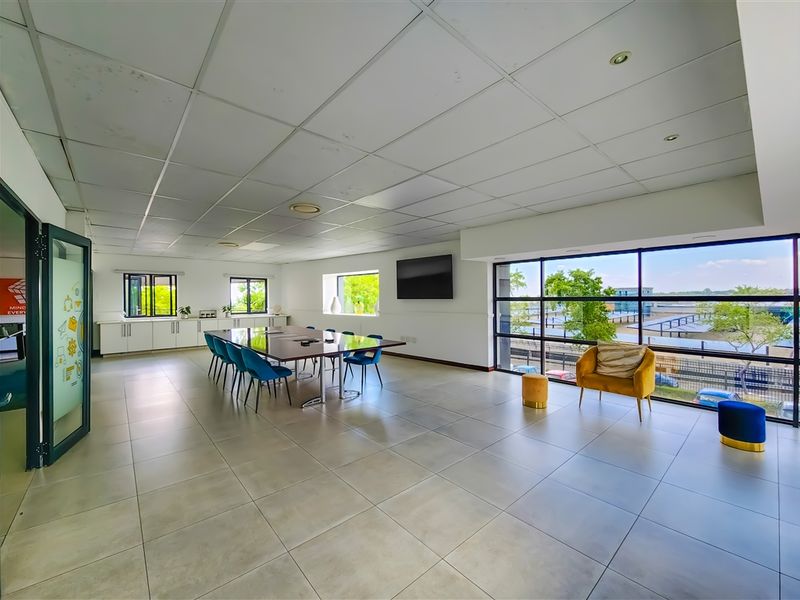 Spacious office area featuring large windows, tiled flooring, and a suspended ceiling with integrated lighting, offering a bright and functional workspace.